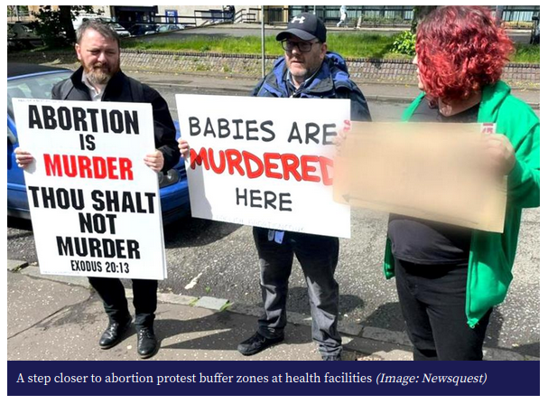 This image shows three individuals participating in an anti-abortion protest. The two on the left hold signs with messages opposing abortion, while the person on the right holds a sign with a message that's obscured. The placards include phrases like \"ABORTION IS MURDER\" and \"BABIES ARE MURDERED HERE,\" along with a reference to a Bible verse, suggesting the protest has a religious component. The caption at the bottom of the photo indicates that this scenario is related to a discussion about implementing buffer zones at health facilities, which is likely a measure to limit such protests near these facilities for patient privacy and safety.